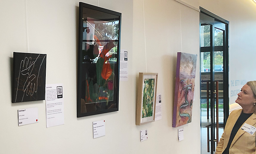 Photo of Amanda Cranage looking at artworks hanging on the wall in a gallery.