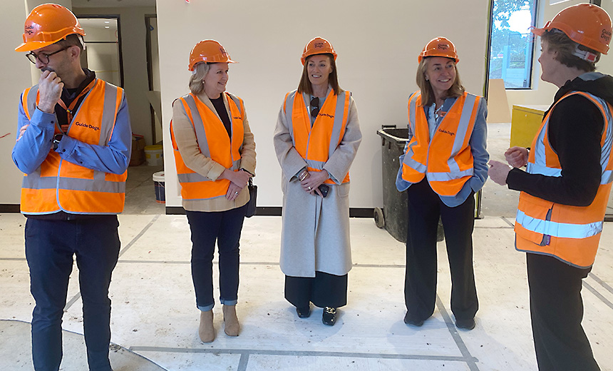 Dr Russell Harrison, Amanda Cranage, Siobhan Todhunter and Nicky Long stand together with a guide giving them a tour of the redevelopment site. Everyone is wearing orange safety vests and orange hard hats.