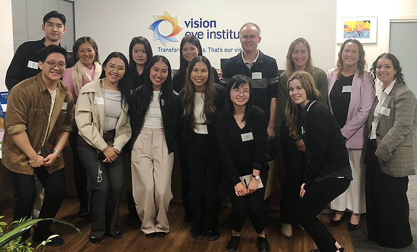 A group of 14 OPSM optometrists pose for a photo, all smiling at the camera.