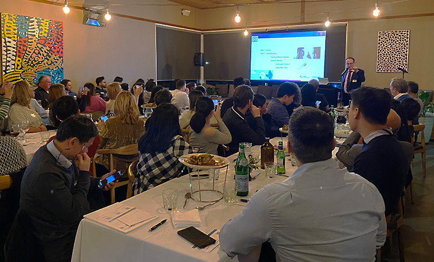 Dr Lewis Levitz presenting to attendees sitting at long dining tables at The Boathouse in Maribyrnong Park.