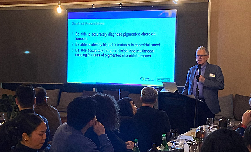 Dr John McKenzie presenting to optometrists at The Boathouse, Maribyrnong Park. The slide on the projector screen says: Goals of Presentation 1. Be able to accurately diagnose pigmented choroidal tumours 2. Be able to identify high-risk features in choroidal naevi 3. Be able to accurately interpret clinical and multimodal imaging features of pigmented choroidal tumours.