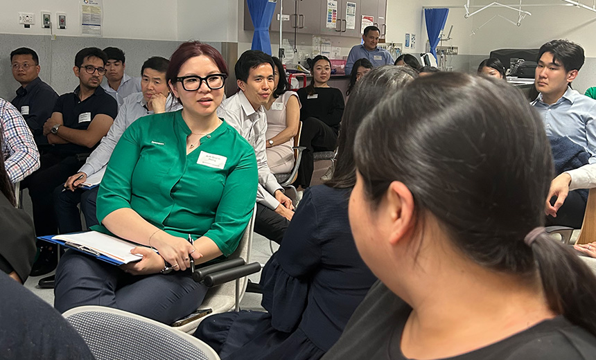 A photo of a large ophthalmology clinic room filled with young professionals sitting on chairs. They appear to be attending a presentation.