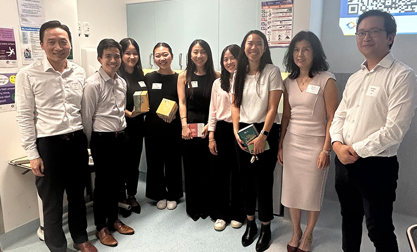 A photo of Dr Tess Huynh and some other Vision Eye Institute doctors standing with some young professionals and smiling. They appear to be in an office kitchen.