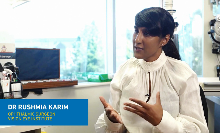 Dr Rushmia Karim wearing a high-necked, white blouse sits to the right of the frame in her consulting suite; she is talking to an unseen person to the left.