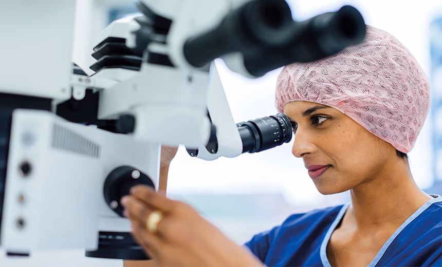 Dr Christolyn Raj wearing medical scrubs and a theatre cap while using laser eye surgery technology.