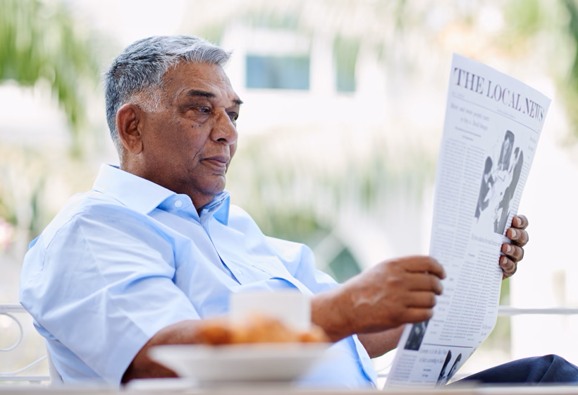 A photo of an elderly man reading a newspaper.