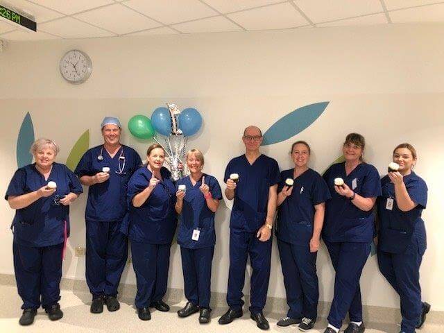 Dr Neil Maycock, Dr John Argyrides and Windsor Gardens Day Surgery staff group photo dressed in scrubs
