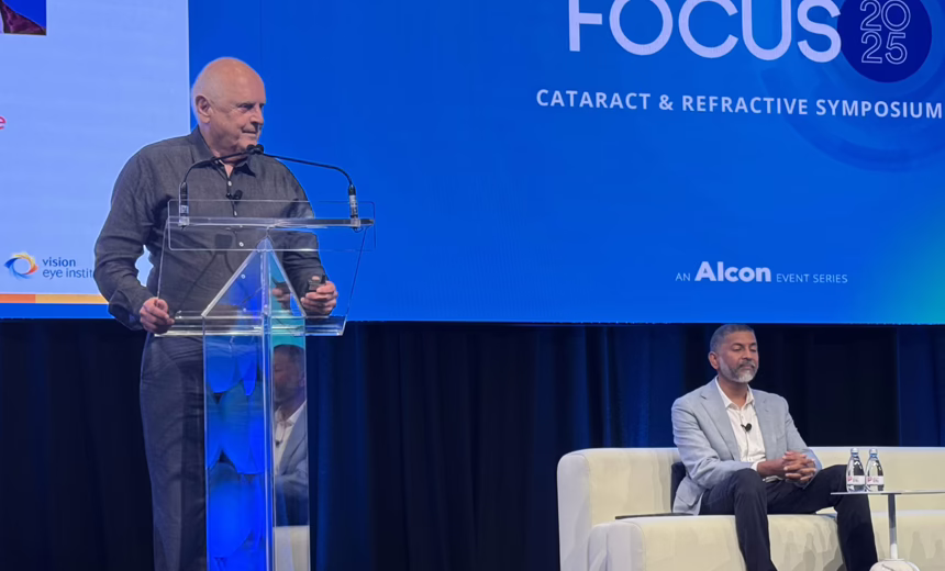 A photo of Dr Reich presenting at the Alcon meeting. Dr Bala is seated on stage.