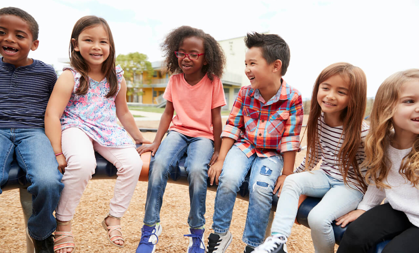 Group of happy, young children (mixed ethnicity) outside – one has child myopia and wears glasses