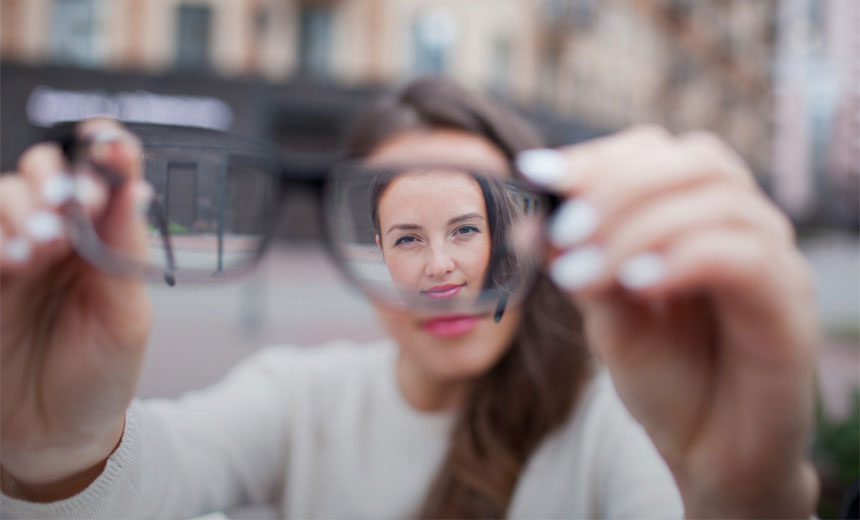 Girl holding glasses with image in focus only through lens