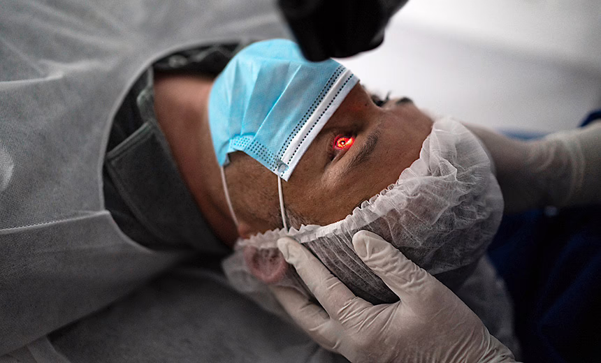 Patient wearing mask and gown lying down having eye operation