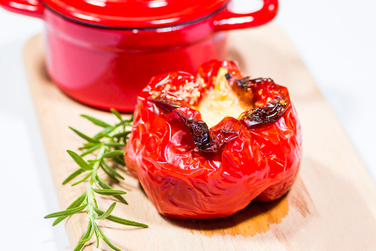 Stuffed red pepper and red saucepan closeup shot