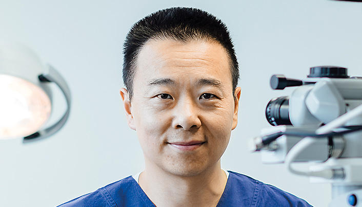 Dr Simon Chen standing in the operating room dressed in surgical scrubs