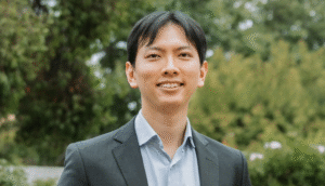 Hero headshot of Ophthalmologist Dr Paul Sia outside the Vision Eye Institute Camberwell clinic. The white, heritage house facade and trees are in the background.